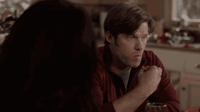 a man in a red jacket is eating a slice of pizza