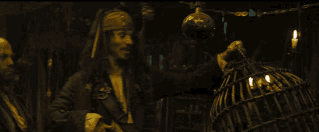 a man in a pirate costume is holding a torch and a bird cage