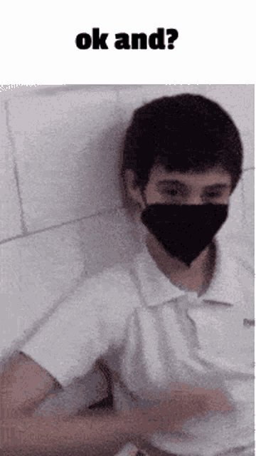 a young man wearing a black mask is sitting on a bed and talking to someone .