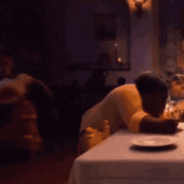 a blurry picture of a person sitting at a table in a dark room