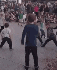 a boy in a blue shirt is standing in front of a crowd of people