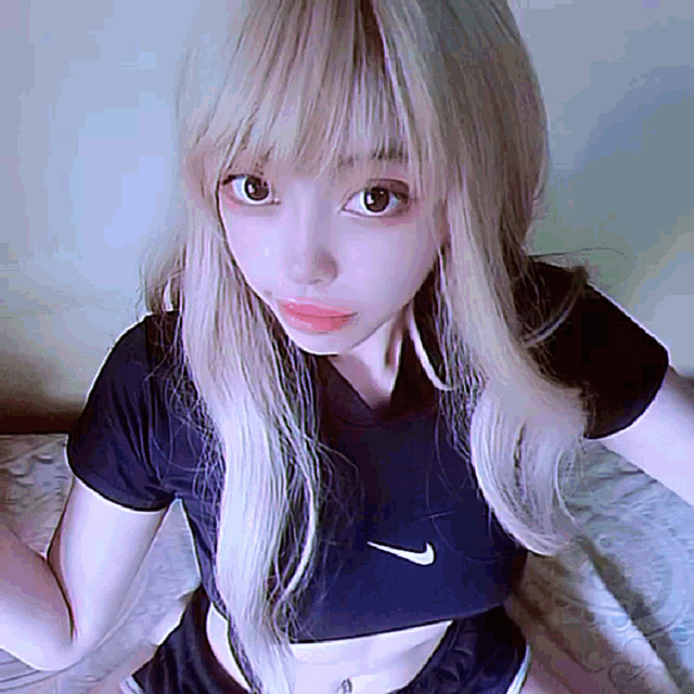 a girl with blonde hair is wearing a black nike crop top