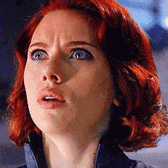 a close up of a woman 's face with red hair and blue eyes looking up .