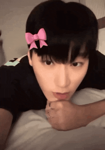 a close up of a person laying on a bed with a pink bow on their head .