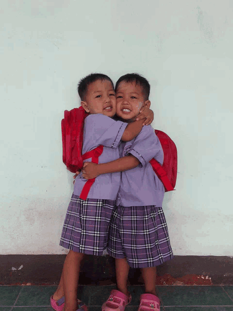 a boy and a girl hugging each other with their backpacks on
