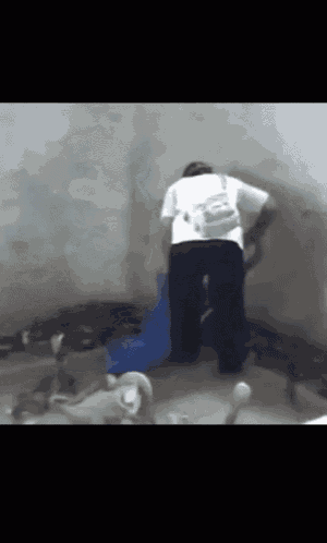 a man in a white shirt and black pants is standing in a room with a backpack on his back .