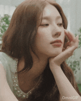 a close up of a woman 's face with her hand on her chin
