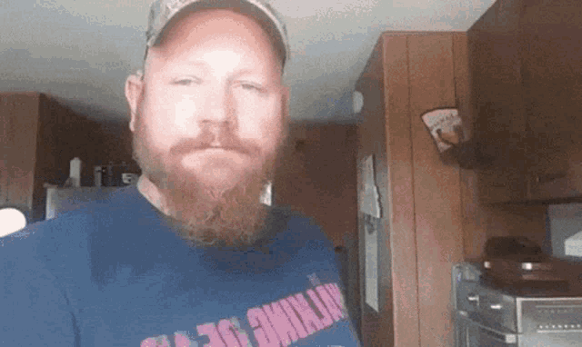 a man with a beard wears a blue shirt that says nothing
