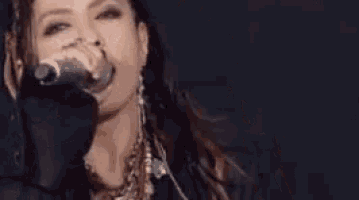 a woman with dreadlocks is singing into a microphone on a stage .