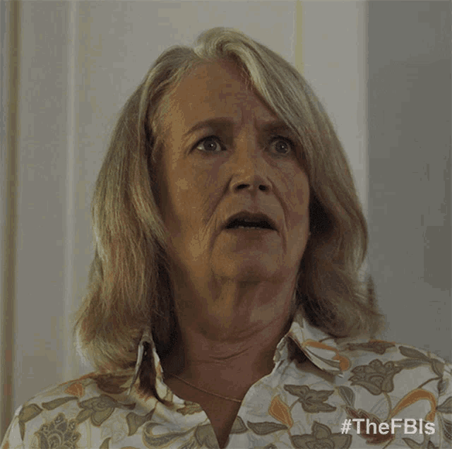 a woman with blonde hair says oh god in a floral shirt