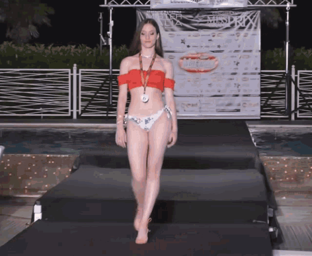 a woman walks down a runway in front of a missprix banner