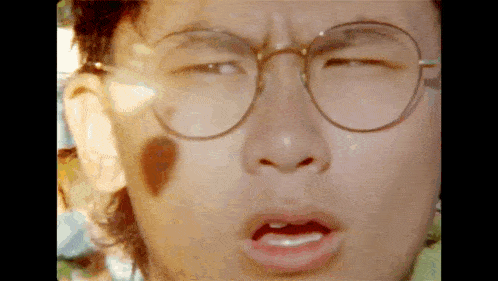 a close up of a person wearing glasses with their mouth open