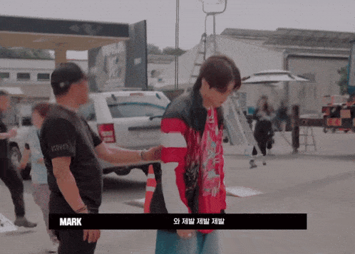 a man in a red jacket is being escorted by a man in a black shirt that says mark