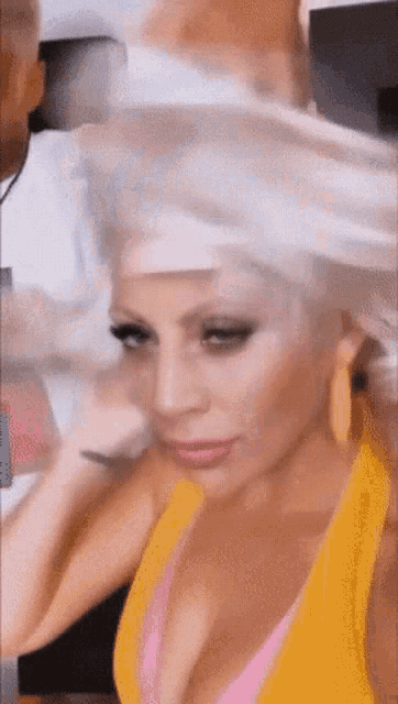 a woman in a yellow tank top has her hair blow dried by a man