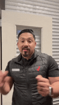 a man with a beard wearing a black vest with a red letter j on it