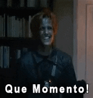 a man in a leather jacket is standing in front of a bookshelf and says que momento !