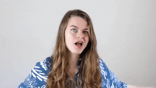 a woman with long hair is wearing a blue shirt and making a face .