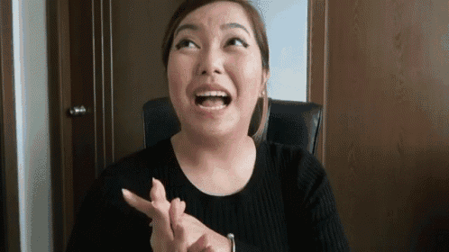 a woman is sitting in a chair with her mouth open and making a funny face with her hands .
