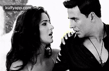 a man and a woman are standing next to each other and looking at each other in a black and white photo .