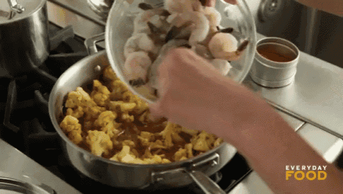 a person is pouring shrimp into a pan with everyday food written on the stove top