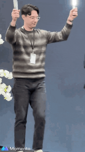 a man with a lanyard around his neck is holding a wii controller in his hands