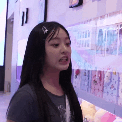 a girl with long black hair is standing in front of a wall with pictures on it including one that says i love you