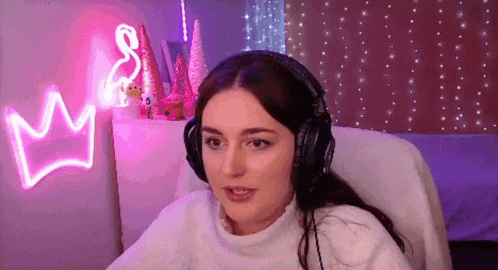 a woman wearing headphones is sitting in a chair in front of a neon sign that says crown .