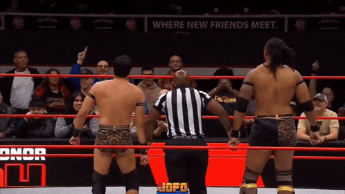 a referee stands between two wrestlers in a wrestling ring