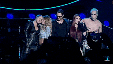 a group of people standing next to each other with a man wearing sunglasses in the middle