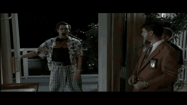 a man in a hawaiian shirt is holding a knife while standing next to a man in a suit and tie .