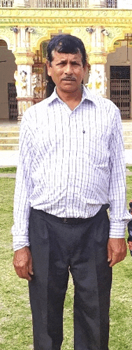 a man in a plaid shirt and black pants is standing in front of a building