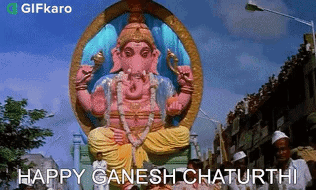 a large statue of ganesha is being paraded down a street in a city .