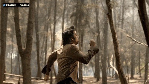 a man in a brown jacket is running through a forest with the hashtag pranay varma