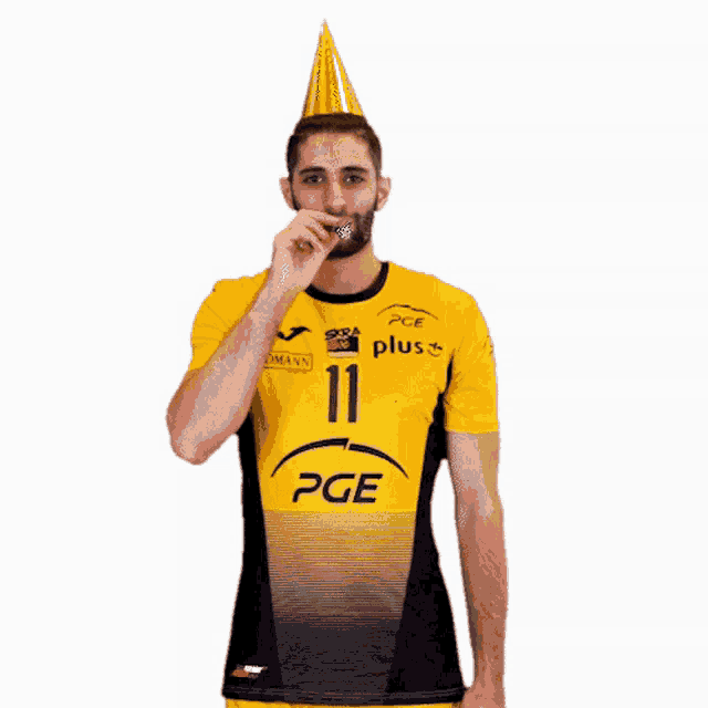 a man wearing a yellow and black pge shirt blows out a candle