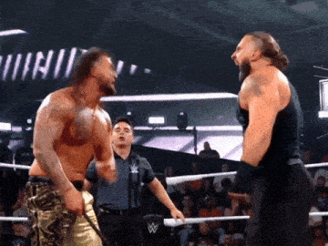 two men in a wrestling ring with a referee and a sign that says ' wwe ' on it