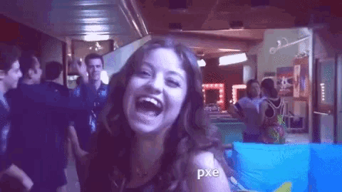 a woman is laughing in front of a crowd of people in a room .