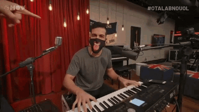 a man wearing a mask is playing a keyboard in front of a microphone