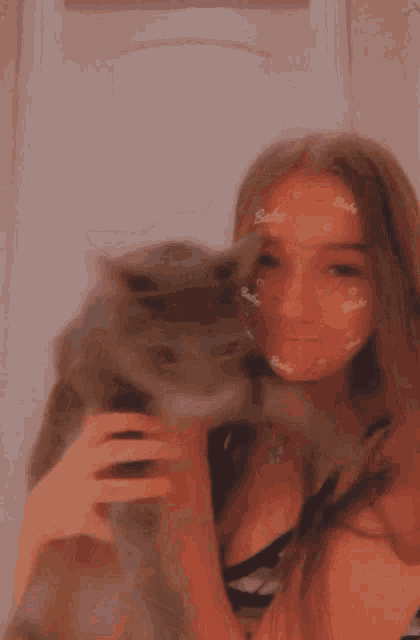 a girl is holding a cat with the word babe written on her face