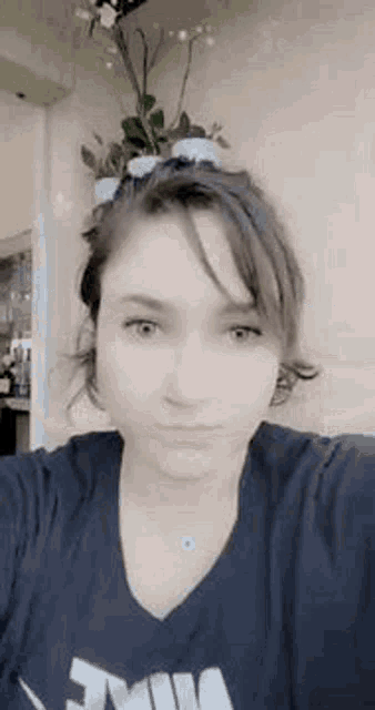 a woman in a black shirt is taking a selfie in front of flowers .