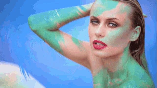 a naked woman with green paint on her face and body
