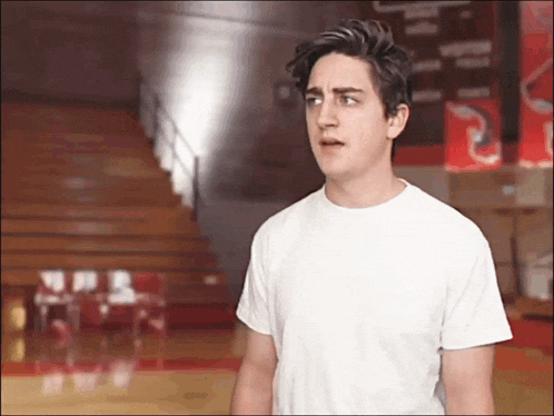 a man in a white t-shirt stands in a gym