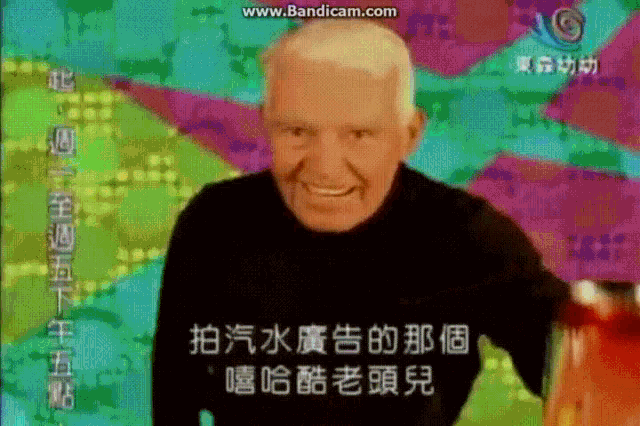 a man in a black shirt is smiling in front of a colorful background with chinese writing on it