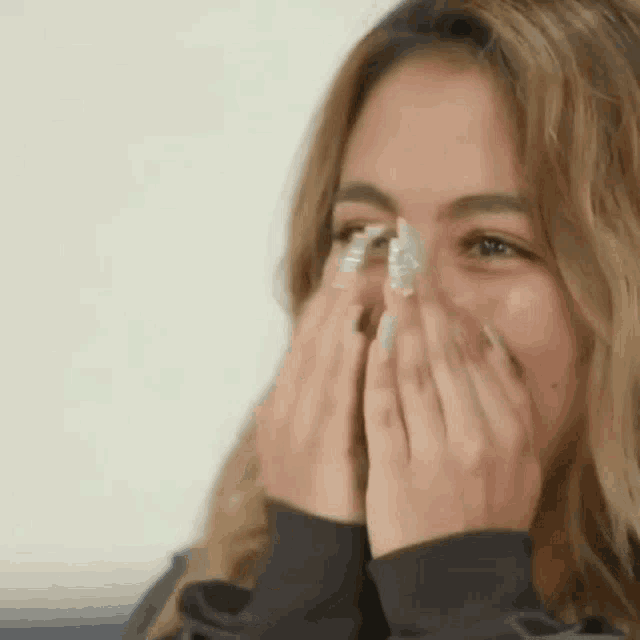 a woman is covering her face with her hands and laughing .