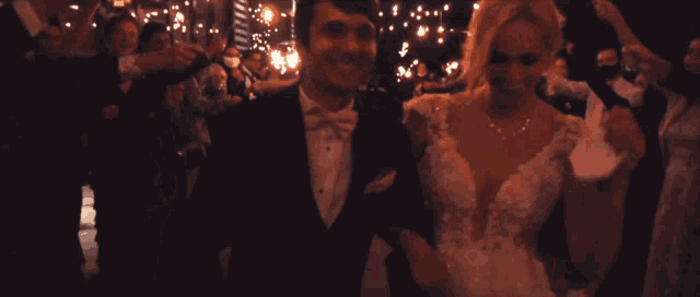 a bride and groom are walking through a crowd of people with sparklers