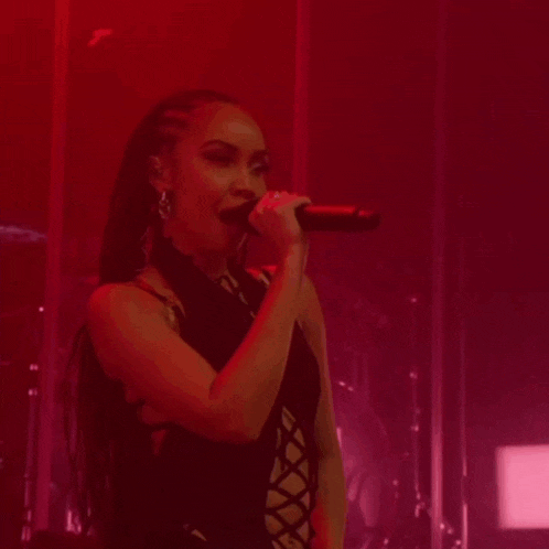 a woman singing into a microphone in a red lighted room