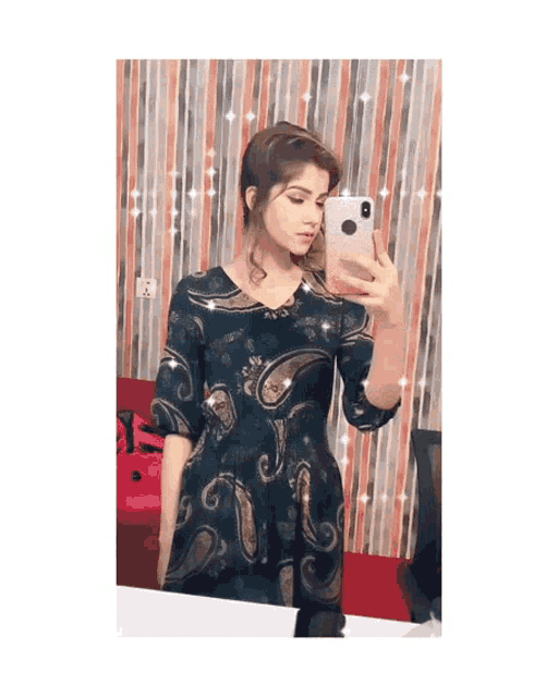 a woman in a paisley dress is taking a picture of herself in a mirror