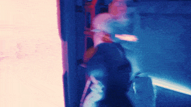 a blurry picture of a person in a room with a blue light behind them