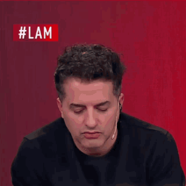 a man with a microphone stands in front of a screen that says #lam on it