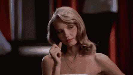 a woman in a strapless dress is sitting at a table with her hand in her hair .