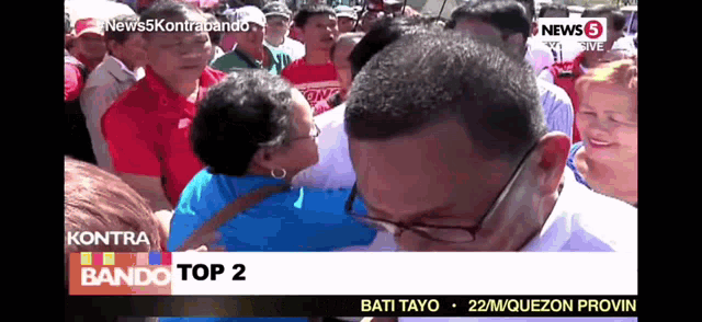 a man kisses a woman on the cheek in front of a news 5 banner